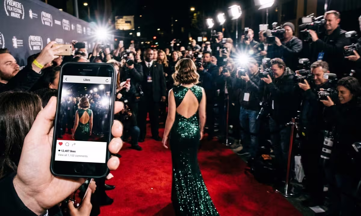 A young actor faces a crowd of raised phones and camera flashes on a red carpet